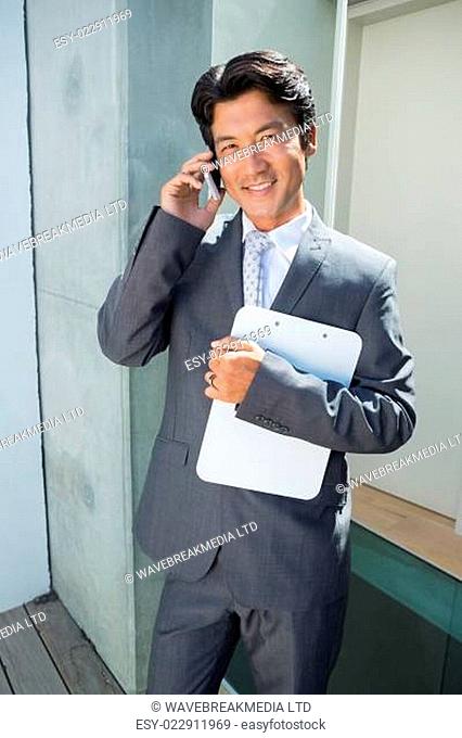 Confident estate agent standing at front door on the phone