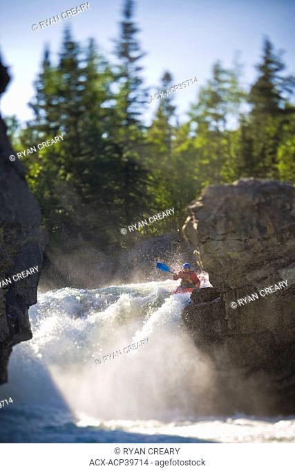 A male kayaker paddles over Elbow Falls, Elbow River, Alberta, Canada