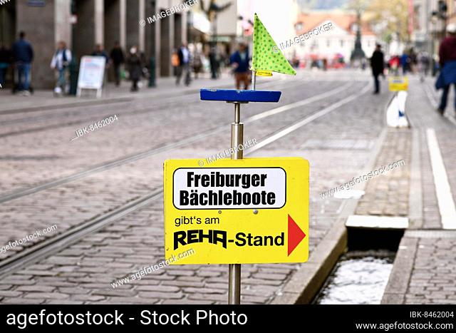 Freiburg, Germany, April 2022: Sign pointing to shop that sells small wooden toy boats children can float on stream called 'Bächle' in city center, Europe