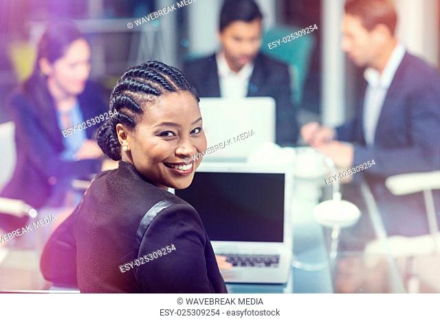 Businesswoman smiling while sitting by colleagues
