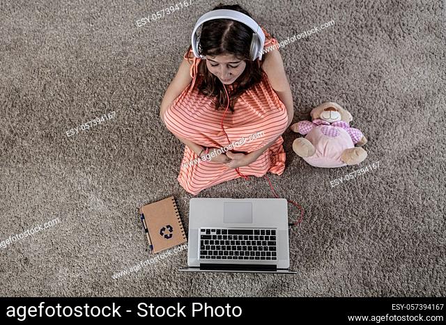 Child sitting near laptop and a notebook