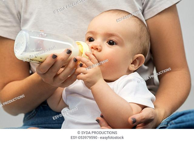 close up of mother feeding baby with milk formula
