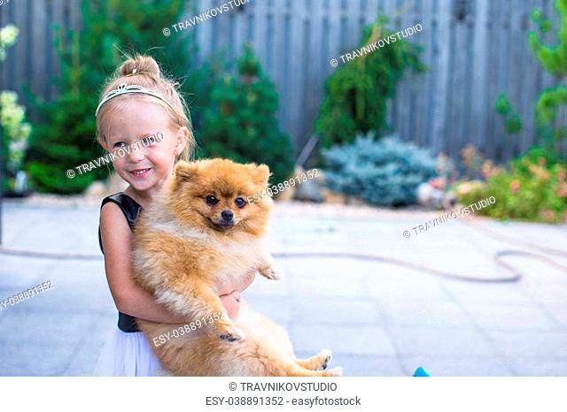 Little blond girl with her pet dog outdoor in park
