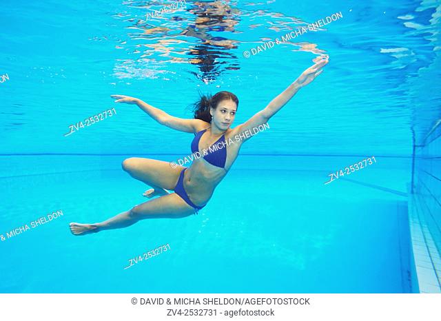 Young woman wearing a bikini while swimming under water in a open-air pool