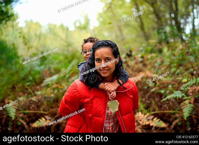 Portrait mother piggybacking son on hike in woods
