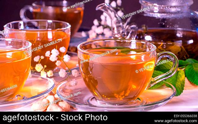 Teapot and mugs with green tea, cashew nuts, green leaves and white gypsophila flowers.Tea ceremony, traditional drink. Afternoon tea, homelike