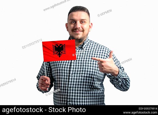 White guy holding a flag of Albania and points the finger of the other hand at the flag isolated on a white background