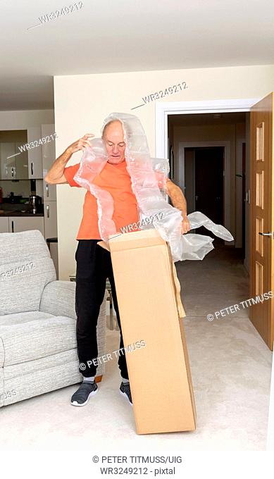 Man unpacking a brown cardboard box containing an excessive amount of protective air bags