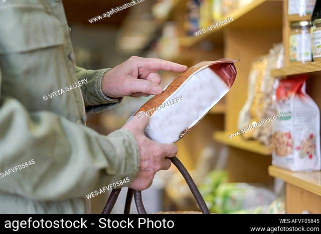 Close-up of senior man buying groceries in a small food store checking ingredients
