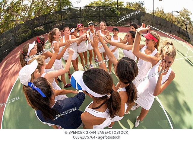 Uniformed tennis players form an arm in arm ceremonial circle before a game in San Juan Capistrano, CA