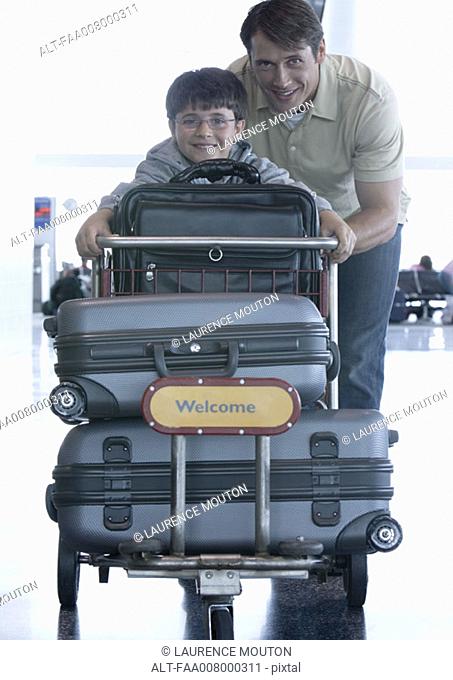 Man and boy pushing luggage cart