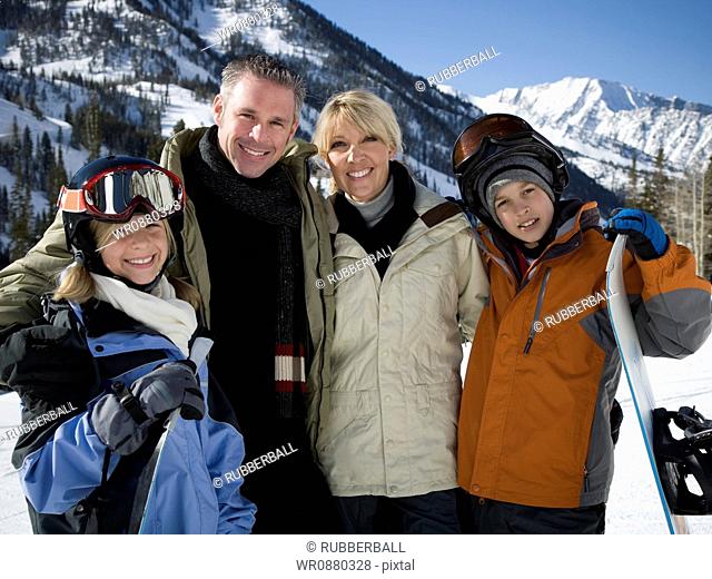 Portrait of a mid adult couple and their children holding snowboards