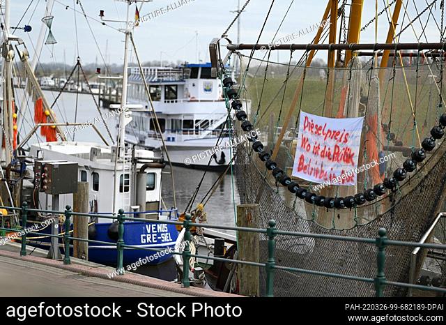 26 March 2022, Lower Saxony, Greetsiel: A banner reading ""Diesel price. Where is the policy. Companies in need"" hangs on a fishing cutter in the harbor
