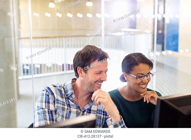 Smiling businessman and businesswoman working at computer in office