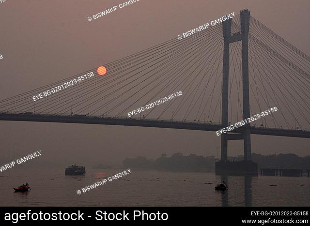 Dec 31, 2022, Kolkata, India. General view of the sunset across the  Howrah Bridge (Vidyasagar Setu) On River Ganges. scenic beauty of the setting sun on the...
