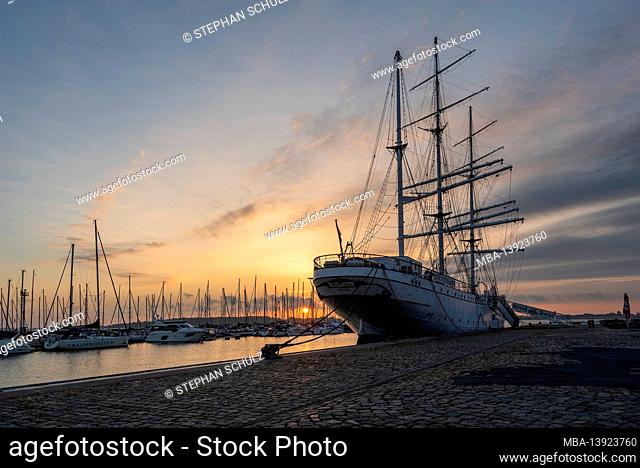 Germany, Mecklenburg-Western Pomerania, Stralsund, sunrise in the city harbor, in the foreground the sailing ship Gorch Fock 1, museum ship