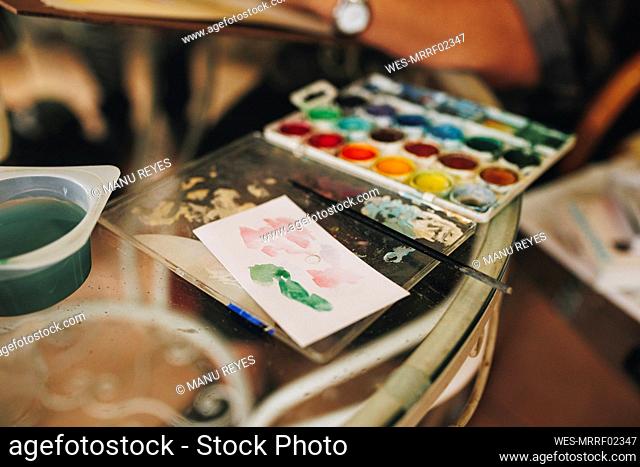 Color palette with paintbrush on table at home