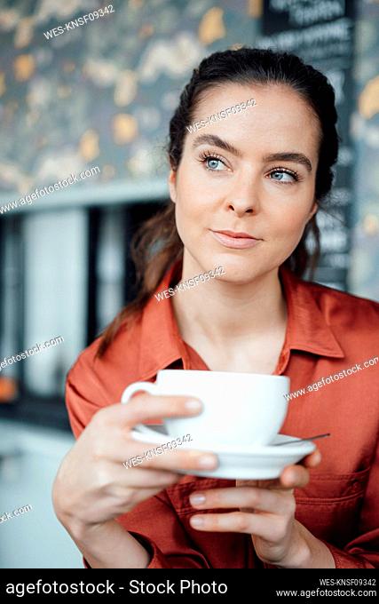 Woman with coffee cup and saucer contemplating in cafe