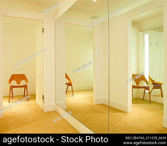 Interior of retail designer clothes shop detail of light spacious change rooms floor length mirrors Interiors shops retailing white walls carpet and a polished...