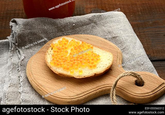 sandwich with red salmon caviar on a wooden board, top view