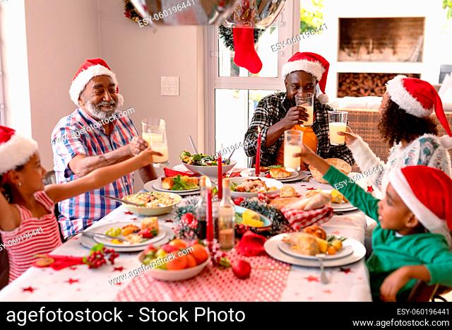 Happy multi generation family wearing santa hats, having christmas meal