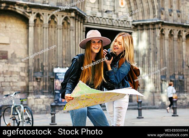 Spain, Barcelona, two happy young women with camera and map