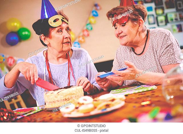 Senior women serving birthday cake at party