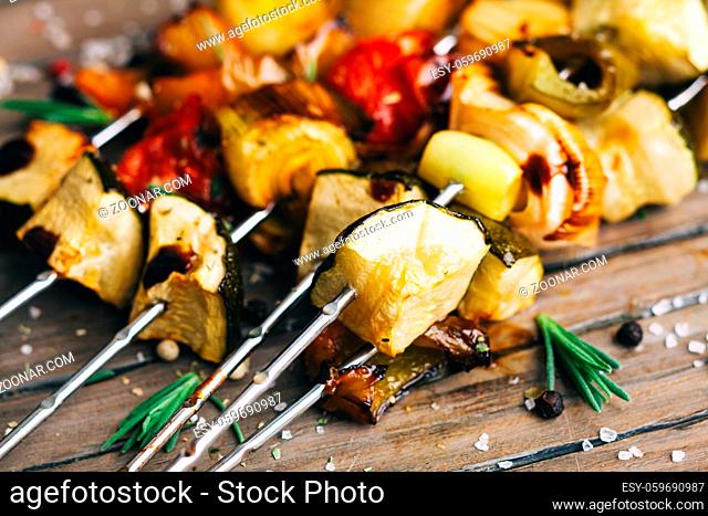 Grilled vegetable skewers with herb marinade on the wooden board, close up