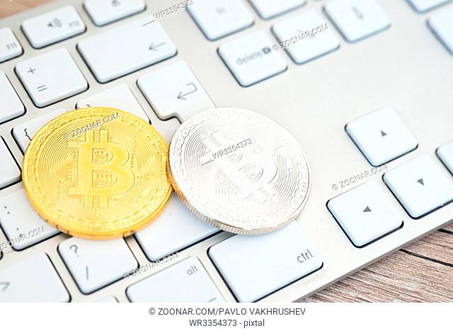 Golden and silver bitcoins lying on a white keyboard