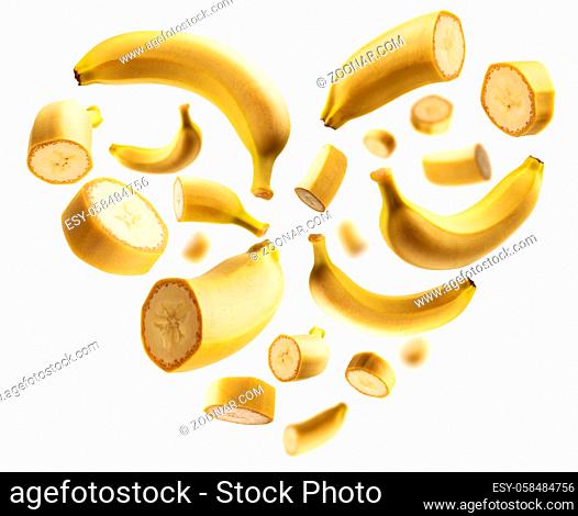 Whole and cut bananas in the shape of a heart on a white background