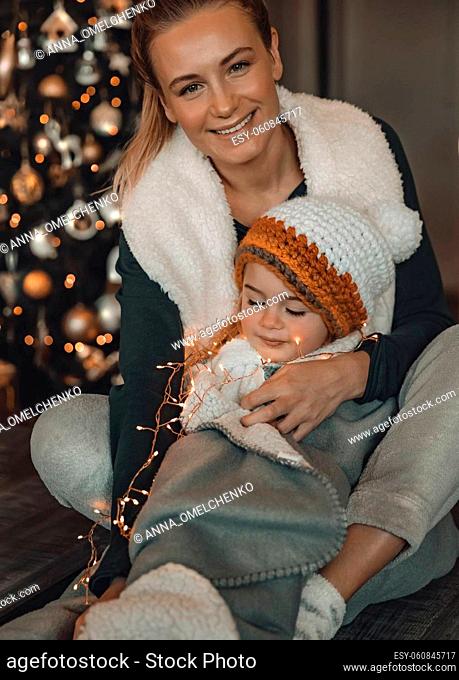 Loving Mom Enjoying Christmas with Her Lovely Baby. Happy Family Decorating Home for Winter Holidays Celebrations. Preparing for Xmas. Happy New Year