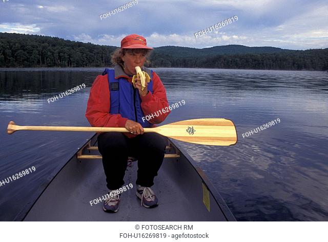 canoeing, canoe, Vermont, VT, Woman eating a banana while sitting in a red canoe on Green River Reservoir in Hyde Park