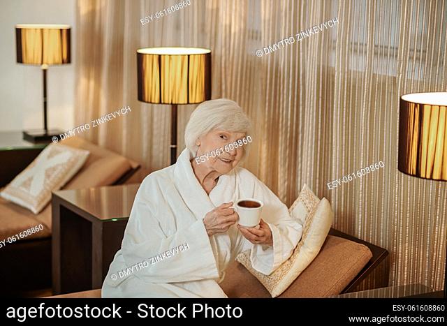 Morning. A good-looking old lady in a white robe in a hotel room