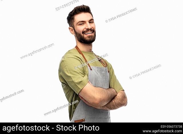 happy smiling barman in apron with crossed arms