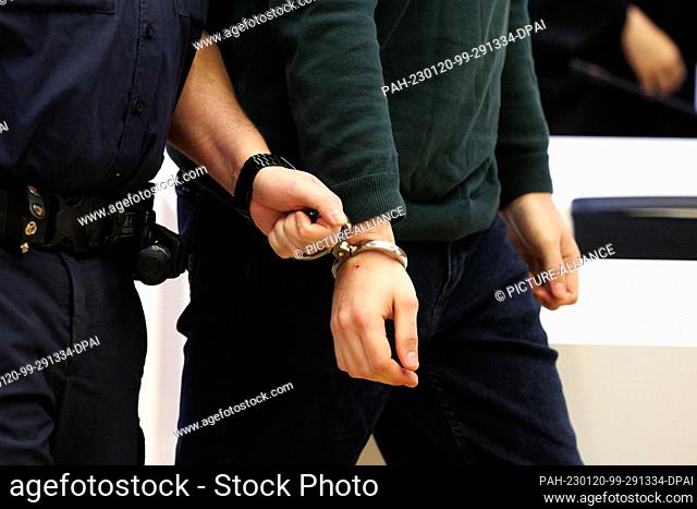 20 January 2023, Bavaria, Munich: One of two men charged with murder is led into the high-security courtroom of the Munich II Regional Court before the start of...