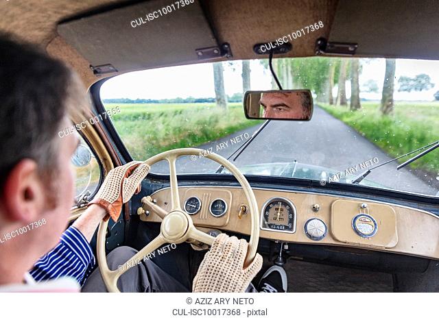 Man driving vintage car on country road
