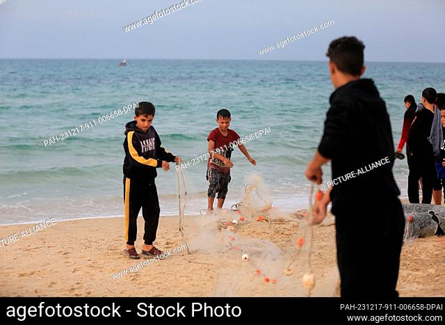 17 December 2023, Palestinian Territories, Rafah: Palestinian children hold a fishing net, as fishermen go fishing, taking a risk to feed their families as...