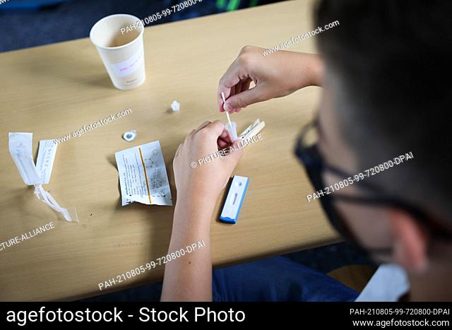 05 August 2021, Hamburg: A pupil in class 6a at the Goethe-Gymnasium in Hamburg-Lurup takes a Corona quick test in the classroom on the first day of school...