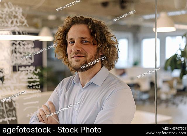 Portrait of confident businessman behind a glass pane in office