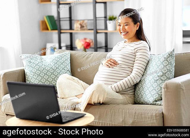 happy pregnant asian woman with laptop at home