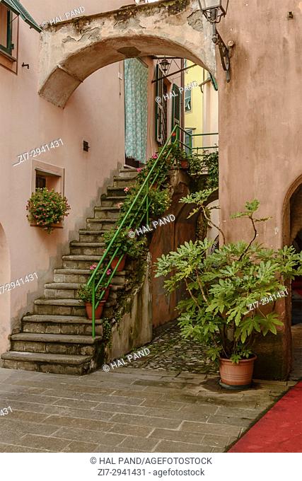 foreshortening of picturesque blossoming stair near covered walkway under old medieval houses , shot in bright late summer light at Varese Ligure, Genova