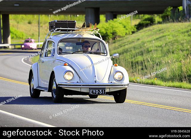 Off-white Volkswagen Beetle, officially Volkswagen Type 1, at speed with luggage and two pairs of skis on roof rack. Salo, Finland. May 18, 2019