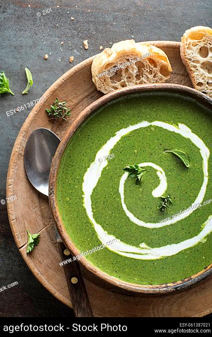 Fresh green soup with cream on grey background overhead shoot