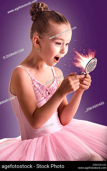 Ballerina children dancer in pink tutu looking in the magic mirror