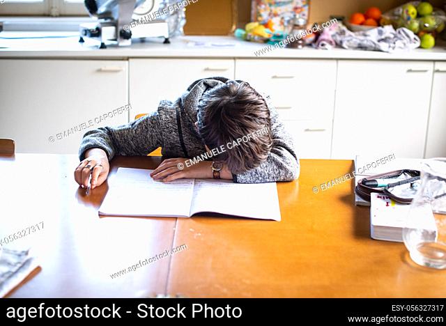 child with his head on the school book desperate cannot do his homework, in the home kitchen