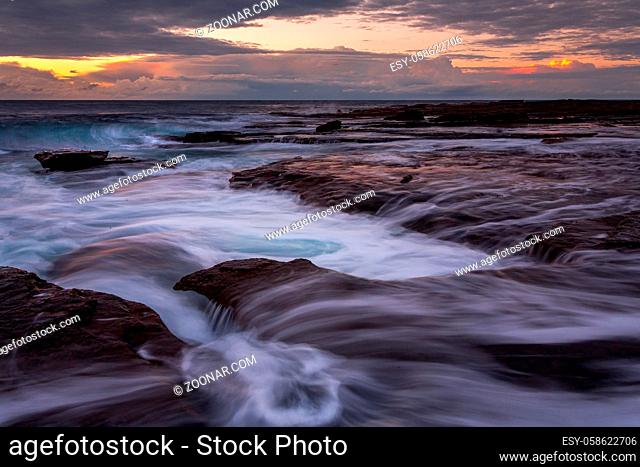 Early morning sunrise views from the edge of the rocky coastline of Coalcliff in the Illawarra region Australia