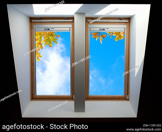 double roof windows overlooking the blue skyand autumn oak leaves