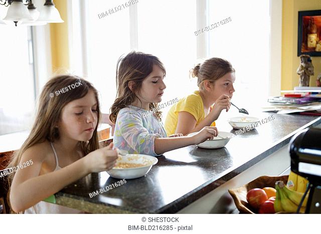 Caucasian sisters eating breakfast in kitchen