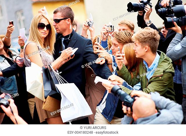 Pretty celebrity surrounded by fans and the paparazzi