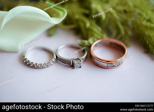 wedding rings on table with calla lilies and greens